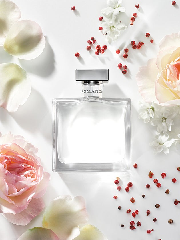 Bottle of Romance fragrance surrounded by flowers & pink peppercorns