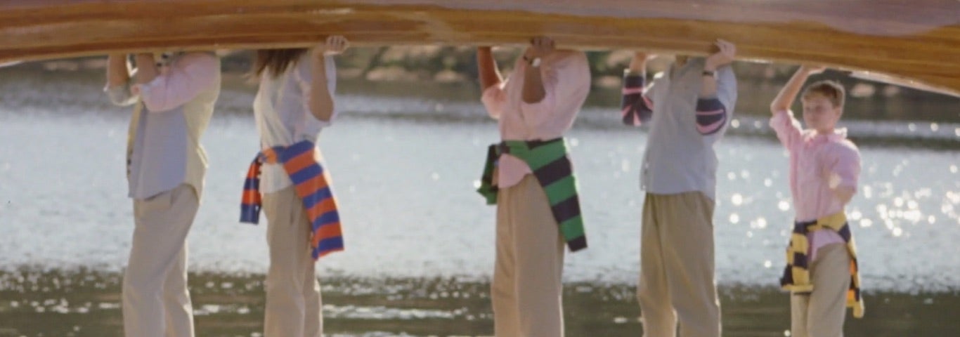 Men & women in chinos carrying a canoe over their heads