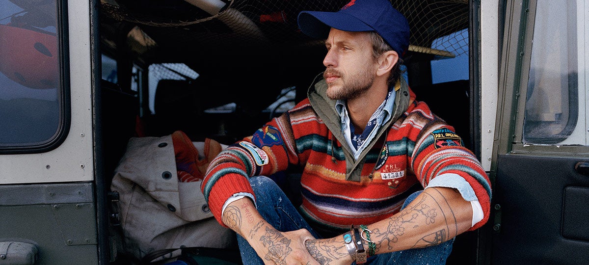 Man in multicolored striped hoodie sitting in back of van